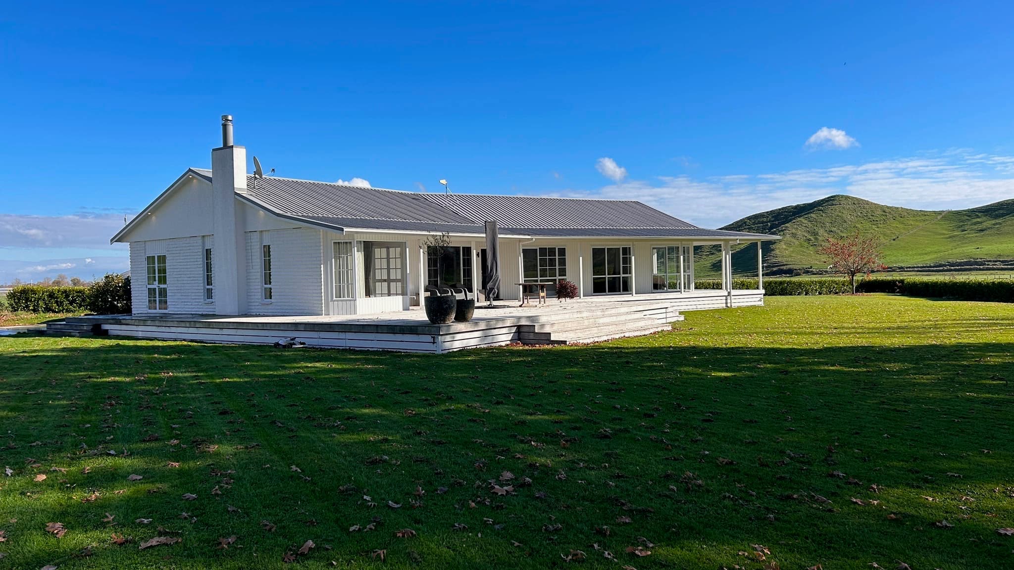 White holiday home with lawn and rural hills